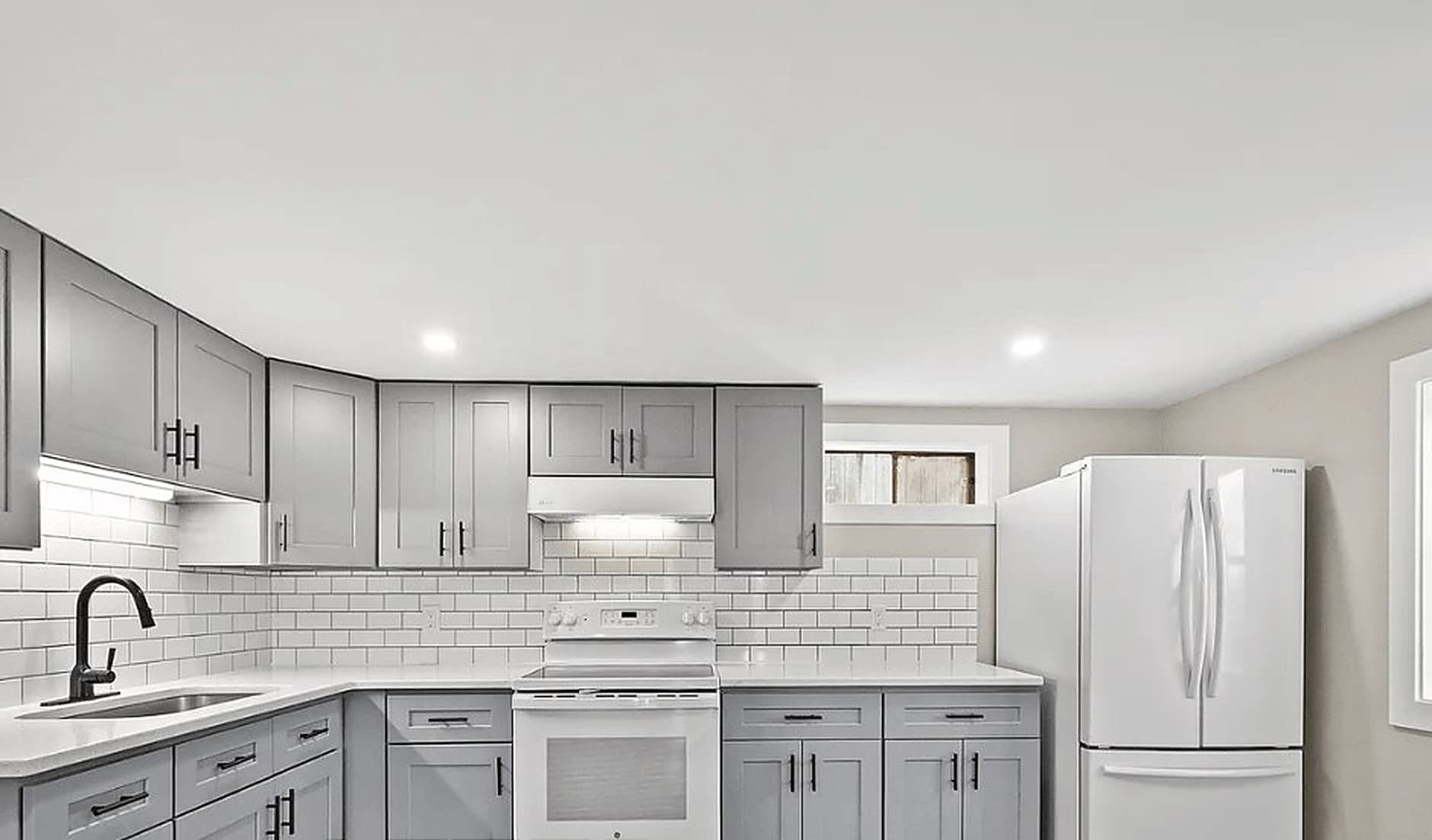 Remodeled kitchen with grey shaker cabinets and white subway tile