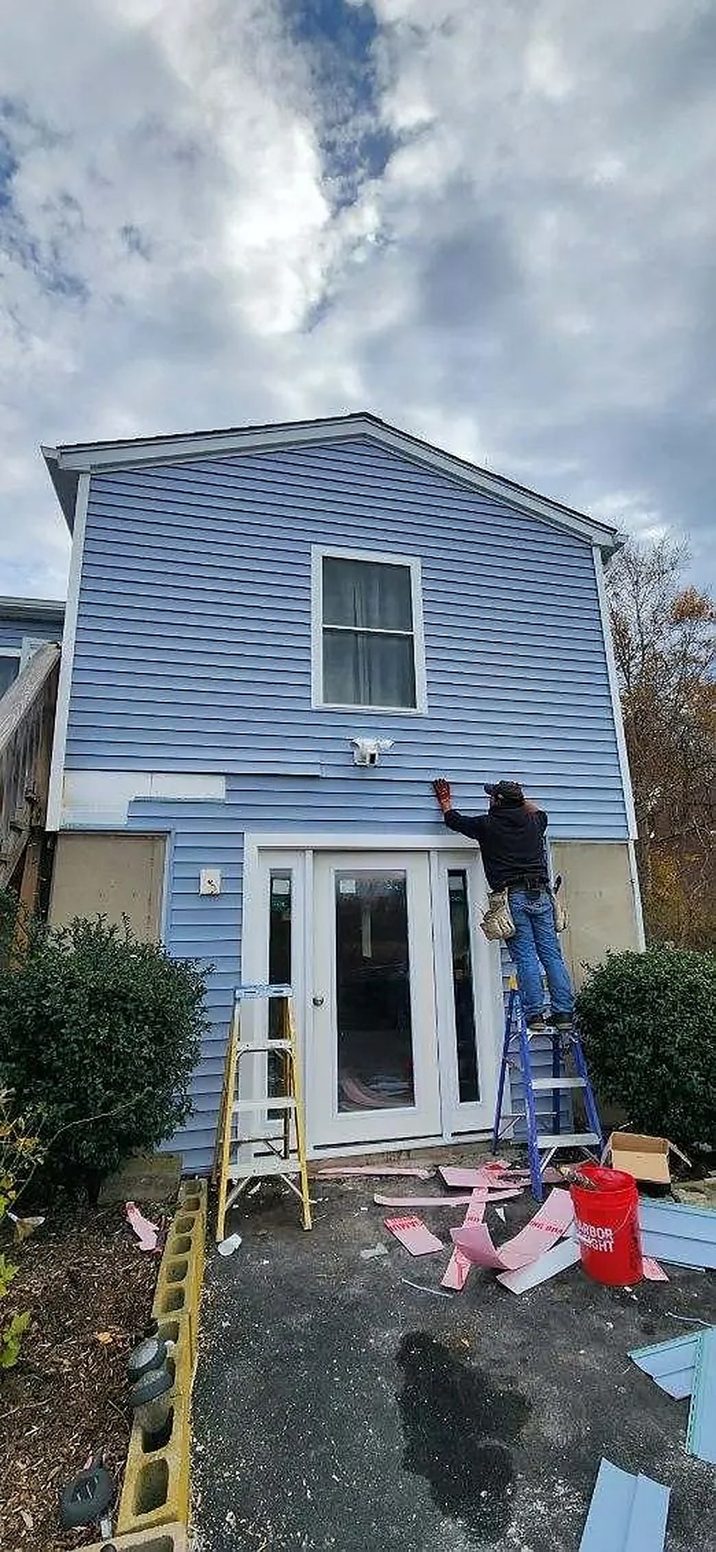 KMAX crew member on a ladder installing new trim on a blue house