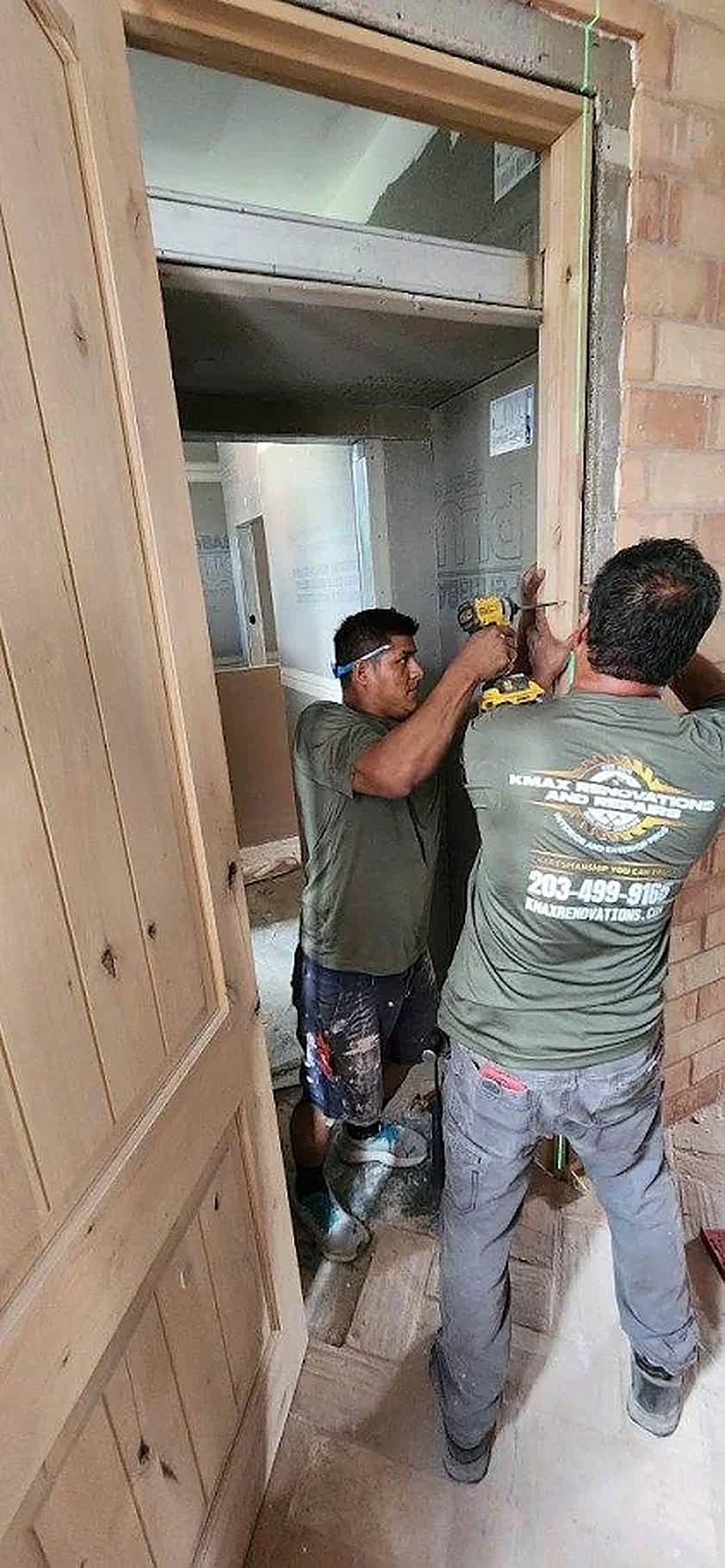 Two KMAX crew members fitting a new solid wood door